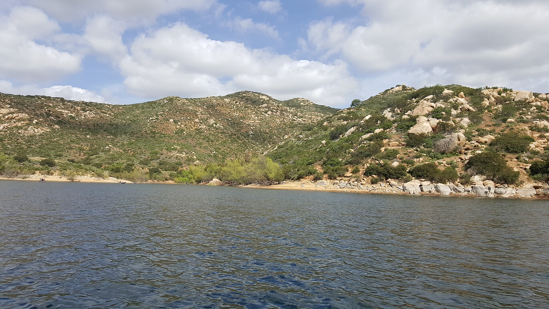 Lake Miramar with chaparral-covered hills under a partly cloudy sky in Scripps Ranch, San Diego