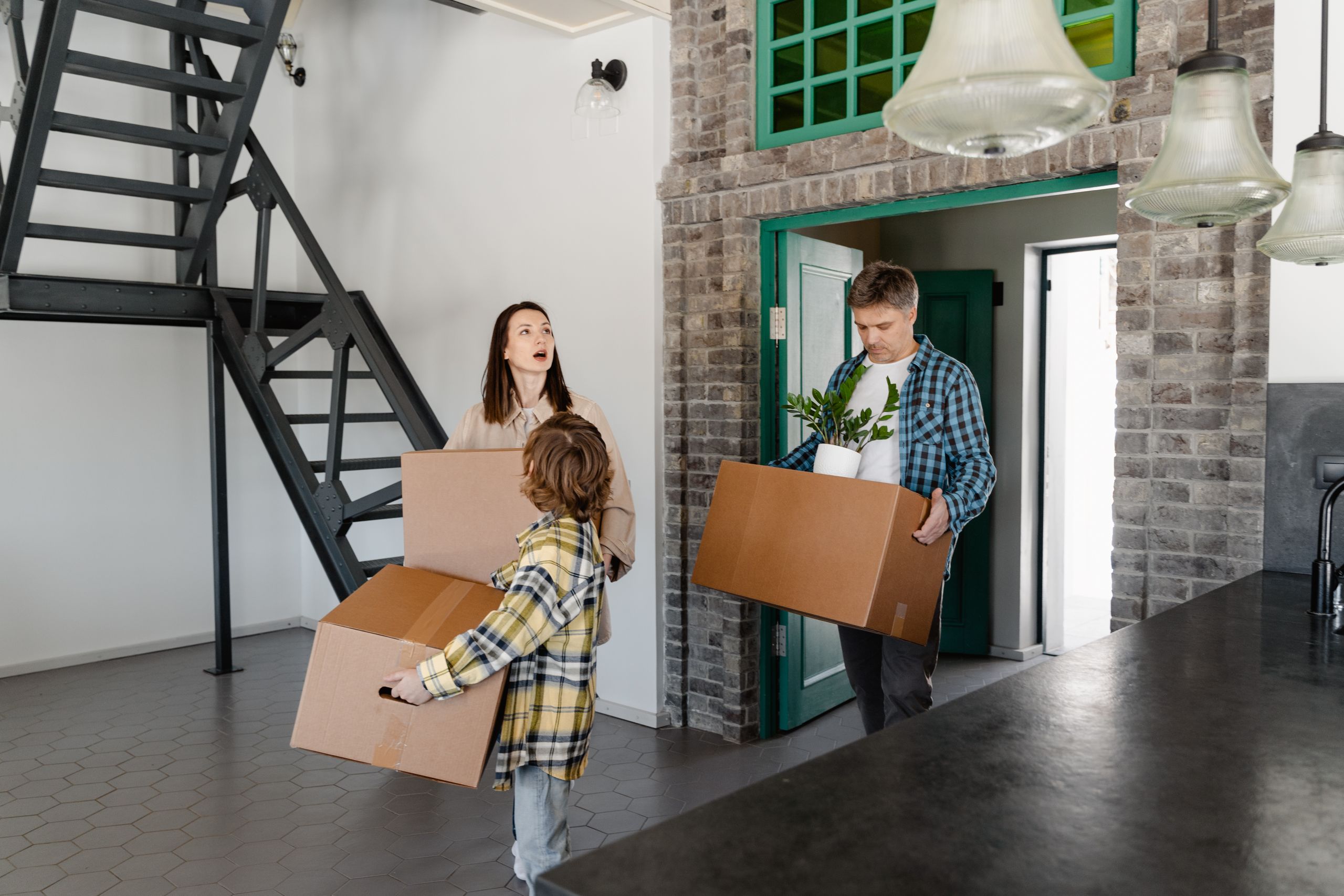 A family carrying moving boxes toward the front door of their new home