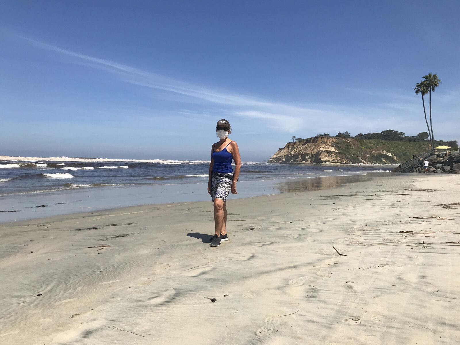 Walkers along the sandy shoreline at Del Mar beach below the bluffs